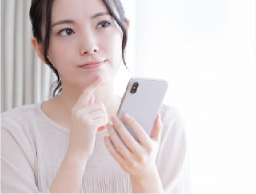 スマホを片手に考えている女性